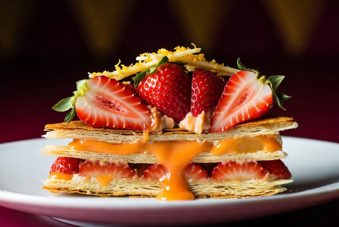 Momozin gourmet: mil-folhas elegante com camadas crocantes de massa folhada, creme sedoso de laranja e morangos frescos vibrantes. Criação RootTaste.