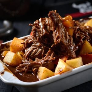 Carne de Panela do Capitão Gancho pronta: carne desfiada suculenta com crosta crocante, batatas, cenouras e molho adocicado pirata em travessa gourmet com tema náutico.