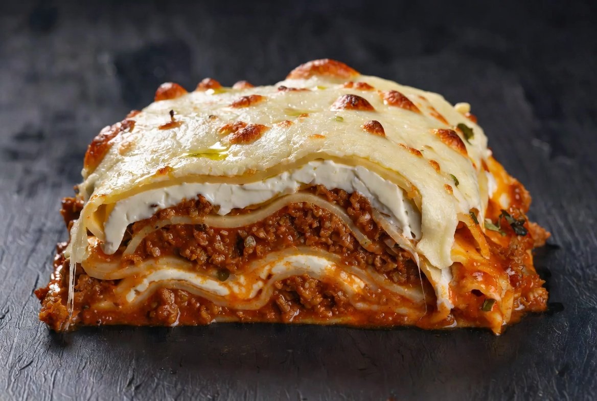 Lasanha da Capitu pronta: camadas generosas de massa fina, ragu traiçoeiro, bechamel sedutor e queijo derretido dourado em estilo gourmet sofisticado.