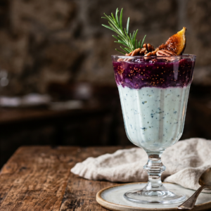 Taça de sobremesa com camadas de mousse de gorgonzola e geleia de figo rústica, decorada com nozes e alecrim em fundo escuro sofisticado.